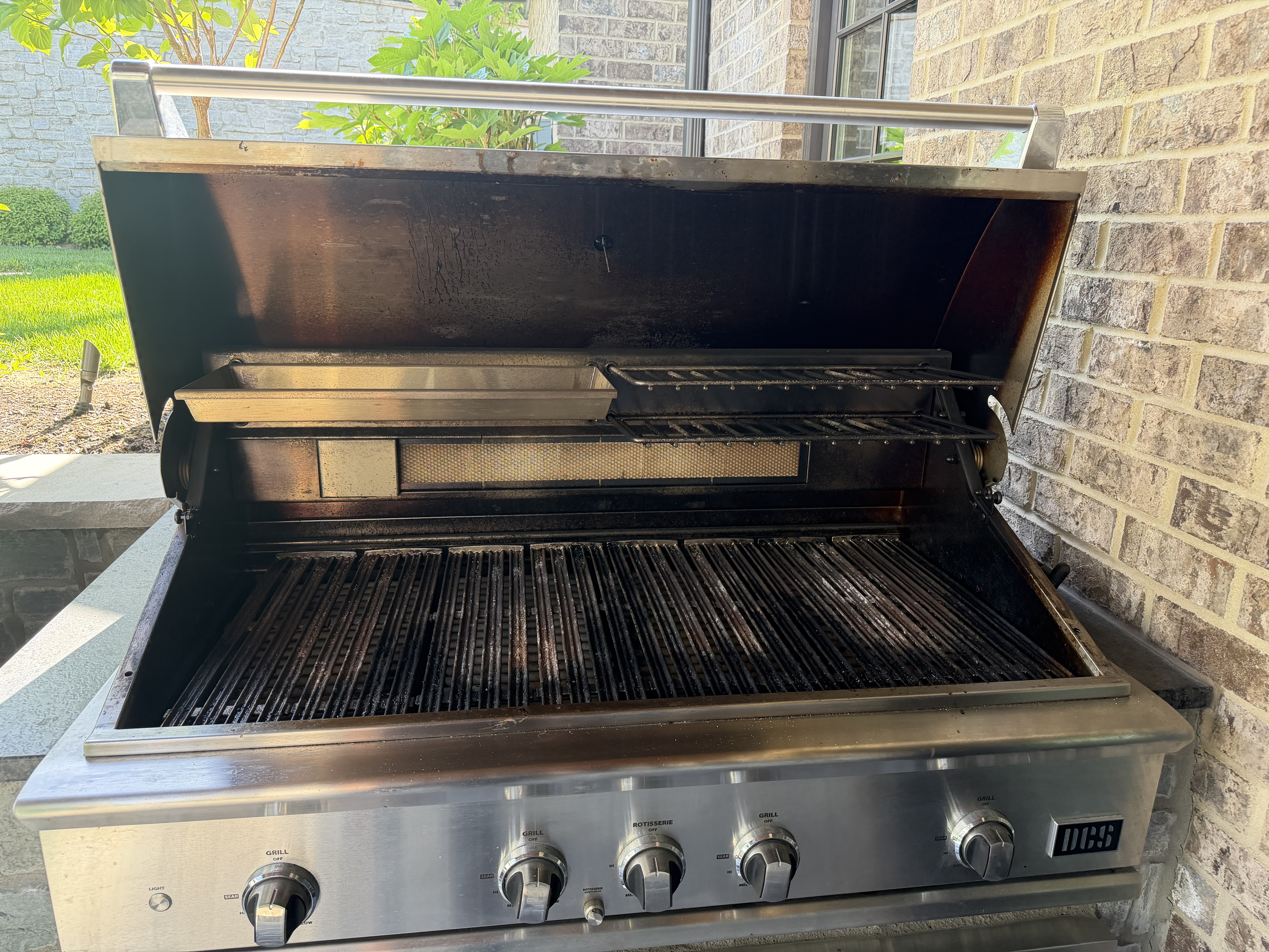 Before: a DCS 5-burner built-in with heavy carbon buildup across the grates and blackened soot on the hood interior
